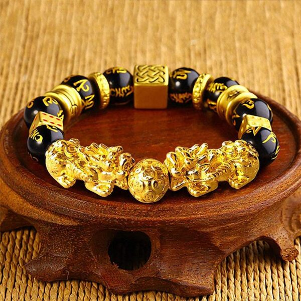 Features bold gold-plated double Pixiu charms and geometric spacers alternating with glossy black obsidian beads engraved with mantras.