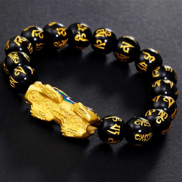 A striking bracelet featuring glossy black obsidian beads inscribed with golden Tibetan mantras, centered by an ornate gold and blue enamel Pixiu charm.