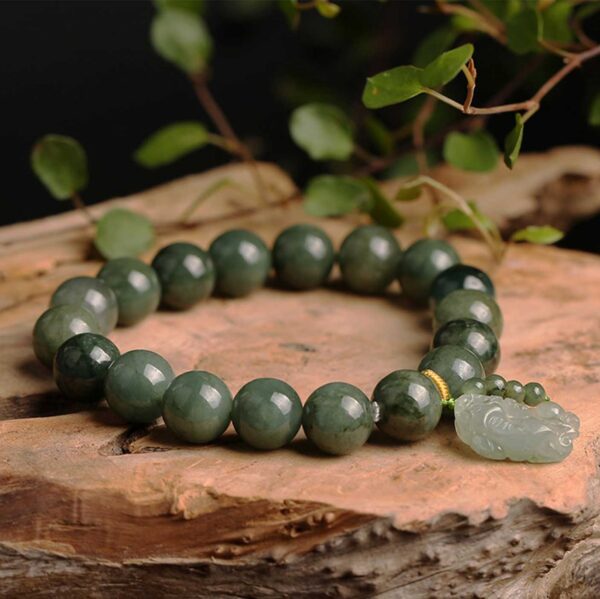 Polished dark green jade beads strung together with a carved light green Pixiu charm and gold accent thread.