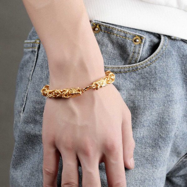 A lustrous gold-plated braided chain bracelet featuring two detailed dragon heads facing each other at the clasp.