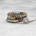 This multi-wrap bracelet features earthy multicolor agate beads strung on brown leather cord with a detailed silver heart charm.