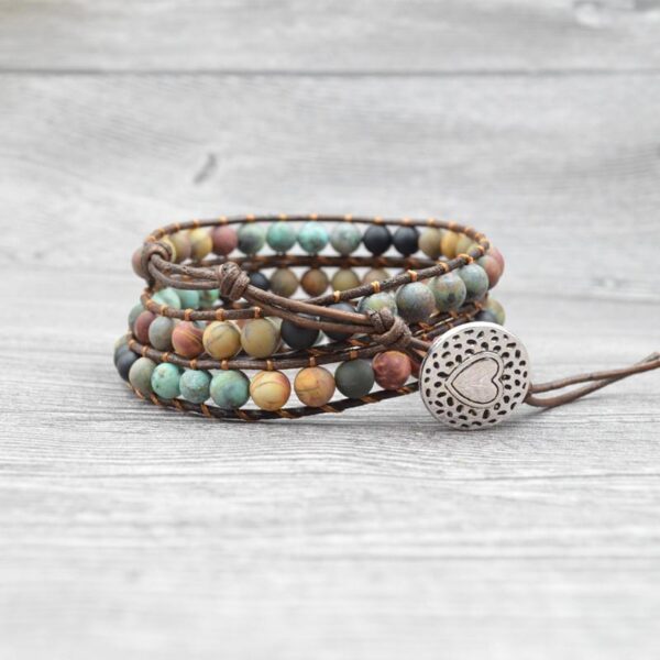 This multi-wrap bracelet features earthy multicolor agate beads strung on brown leather cord with a detailed silver heart charm.