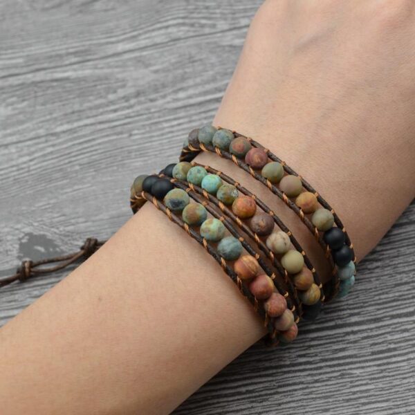 This multi-wrap bracelet features earthy multicolor agate beads strung on brown leather cord with a detailed silver heart charm.