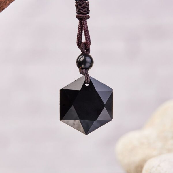 A geometric faceted black obsidian pendant hangs from a braided maroon cord with detailed knotting and a small accent bead.