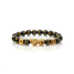 Features glossy black obsidian beads with gold mantras, centered by a golden Pixiu beast and flanked by gold dice charms.