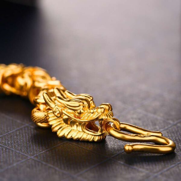 A lustrous gold-plated braided chain bracelet featuring two detailed dragon heads facing each other at the clasp.