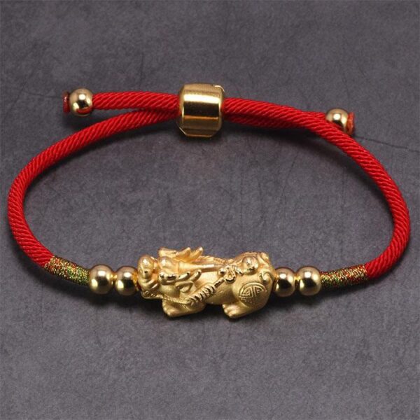 A lustrous gold Pixiu charm centered on a vibrant red braided cord with adjustable gold beads and sliding knot closure.