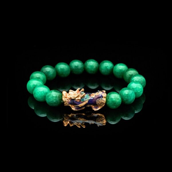 Vibrant green jade beads encircle a striking gold and blue enamel Pixiu charm set against a rustic wooden background.