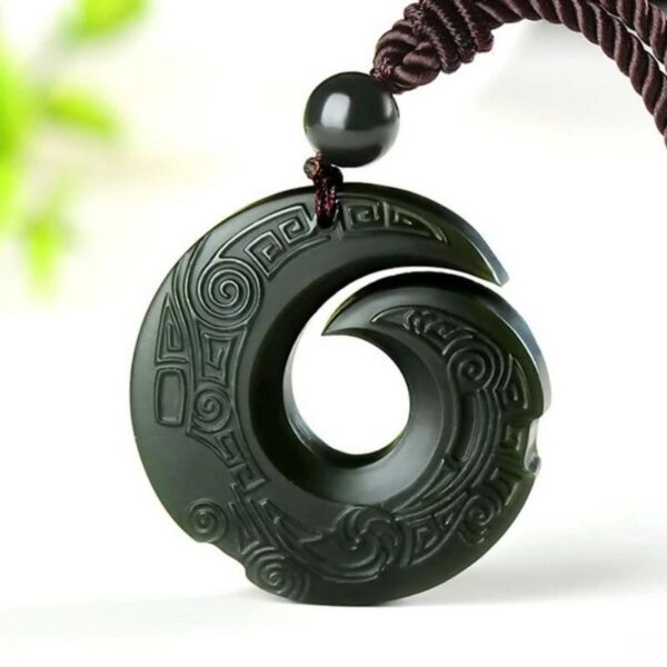 A dark green Hetian jade pendant featuring intricate traditional spiral carvings suspended on a braided brown cord.