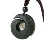 A dark green Hetian jade pendant featuring intricate traditional spiral carvings suspended on a braided brown cord.