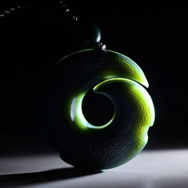 A dark green Hetian jade pendant featuring intricate traditional spiral carvings suspended on a braided brown cord.