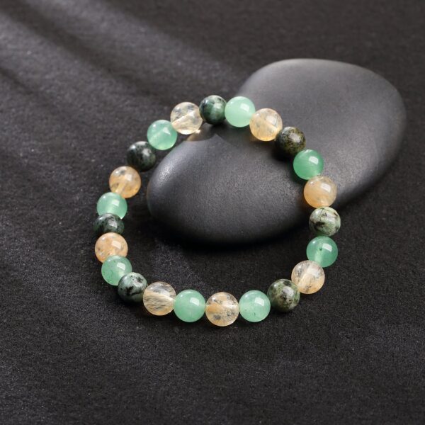 This beaded bracelet showcases an alternating pattern of polished golden citrine, light green aventurine, and speckled dark green turquoise stones.