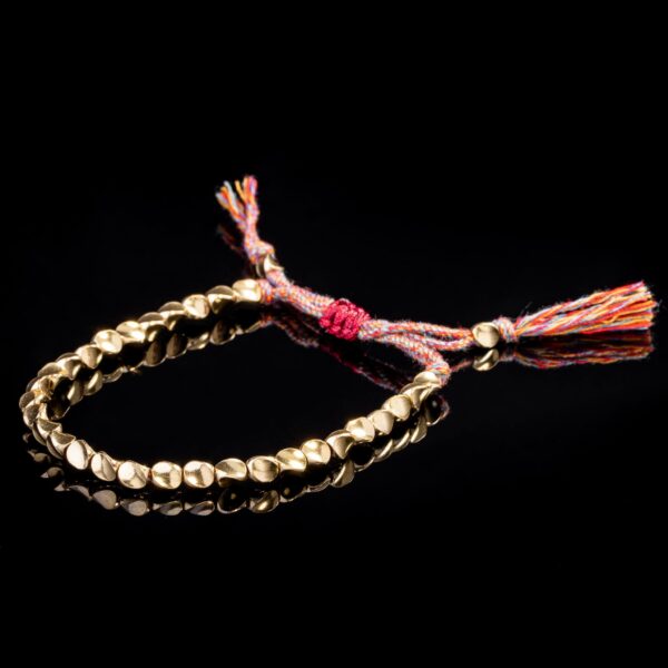 Textured gold-toned copper beads are strung on a vibrant multi-colored cord featuring traditional adjustable Tibetan sliding knots.