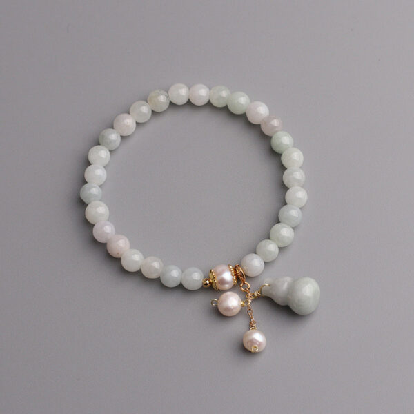 Featuring smooth light green jade beads, this bracelet is elegantly detailed with white pearls and a traditional Wu Lou gourd charm on gold accents.
