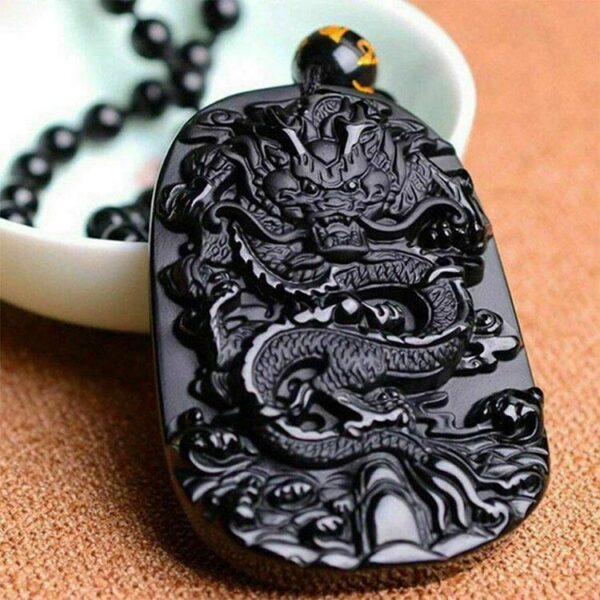 A glossy black obsidian pendant featuring an intricately carved Chinese dragon relief suspended on a matching bead necklace.