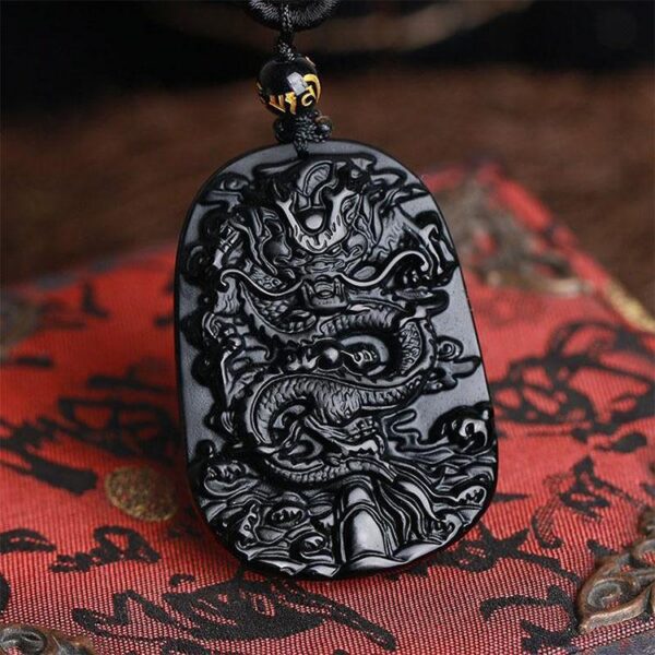A glossy black obsidian pendant featuring an intricately carved Chinese dragon relief suspended on a matching bead necklace.