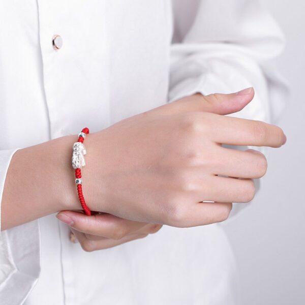A vibrant red braided cord bracelet featuring a detailed sterling silver Pixiu charm and adjustable silver beads.