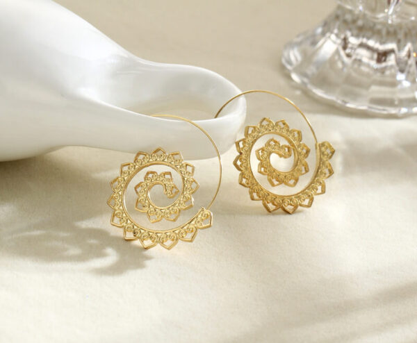 A large gold-toned wire hoop earring featuring an intricate inward spiraling pattern adorned with repeating small heart shapes.