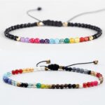 Two adjustable beaded bracelets featuring a spectrum of colorful chakra stones and mixed earth-toned gemstones set against black cords with gold accents.