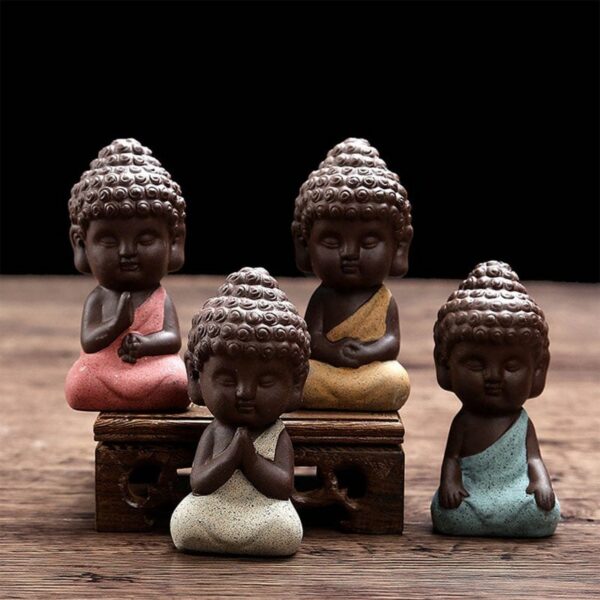 Four charming mini Buddha statues crafted from textured purple sand clay in soothing pastel shades of pink, yellow, beige, and blue.
