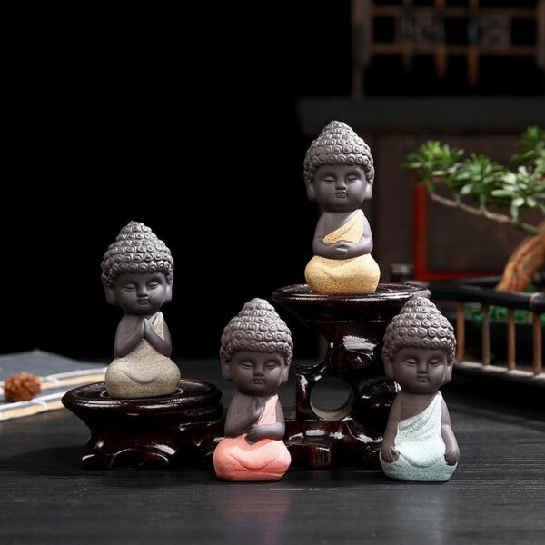 Four charming mini Buddha statues crafted from textured purple sand clay in soothing pastel shades of pink, yellow, beige, and blue.
