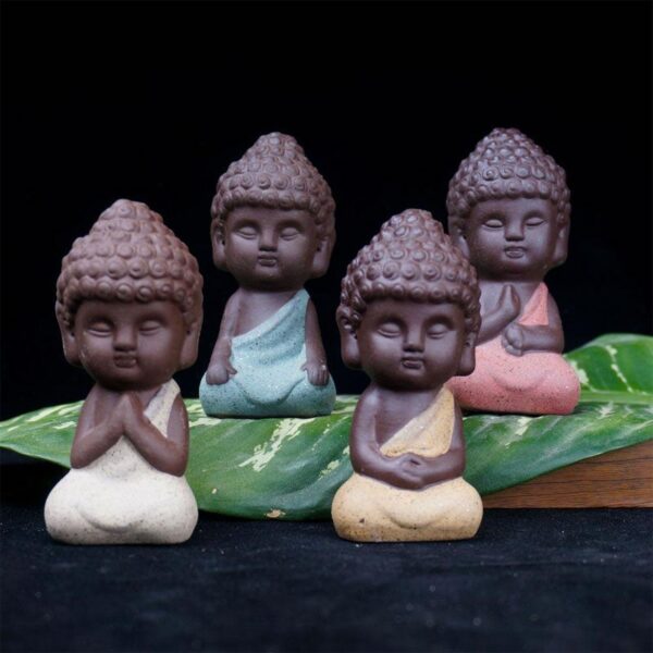 Four charming mini Buddha statues crafted from textured purple sand clay in soothing pastel shades of pink, yellow, beige, and blue.