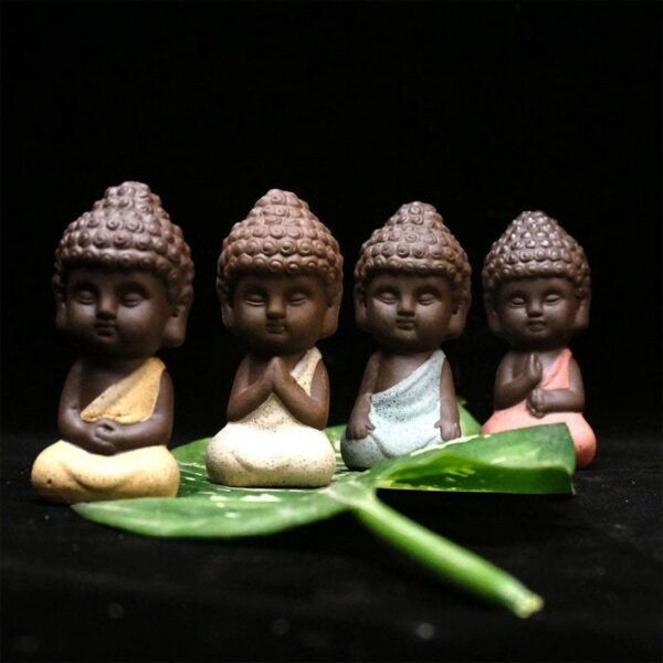 Four charming mini Buddha statues crafted from textured purple sand clay in soothing pastel shades of pink, yellow, beige, and blue.