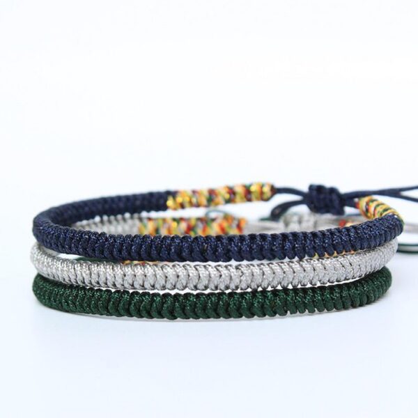 Three stacked braided cord bracelets in deep blue, silver gray, and forest green featuring adjustable Tibetan endless knots.