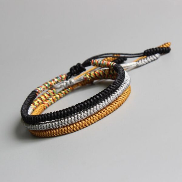 Four intricately braided cord bracelets in black, white, gold, and multi-colors featuring adjustable sliding knots.