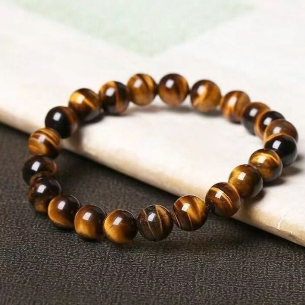 A string of polished golden-brown tiger's eye beads exhibiting a silky chatoyant luster against a soft floral background.